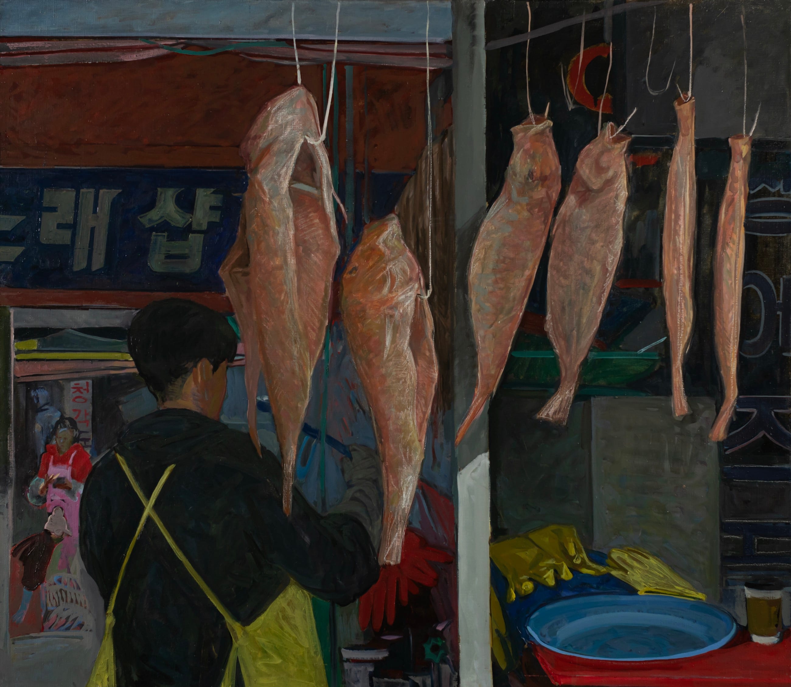 Busan fish market: dried fish hanging on hooks, a vendor in a yellow apron, blue Korean signage